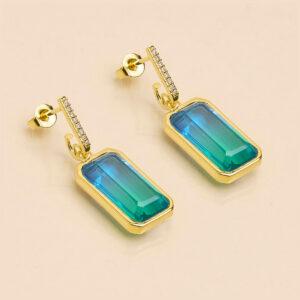 une a une boucles d'oreilles rainbow bleu vert